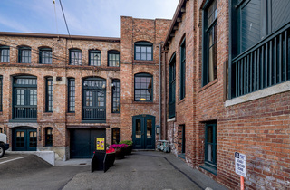 An exterior entrance of a two-story brick building with green divided lite windows.